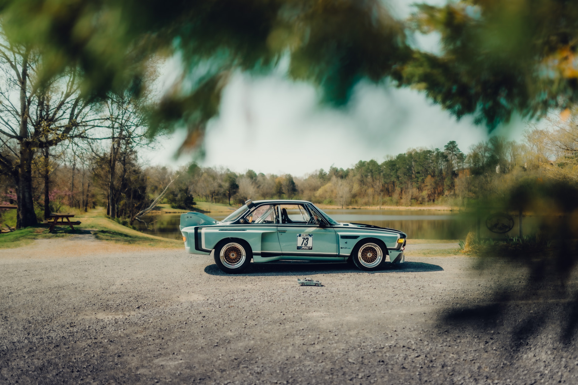 Light blue BMW 3.0 CSL race car parked by a lake